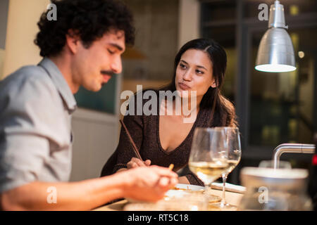 Paio di mangiare la cena con bacchette e di bere il vino bianco a casa Foto Stock