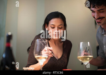 Sorridente giovane mangiare la cena con bacchette e di bere il vino bianco Foto Stock