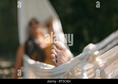 Piedi di donna rilassante in amaca in giardino, close-up Foto Stock