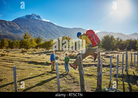 Il Cile, Cerro Castillo, madre di due figli su un viaggio escursionistico saltando paddock recinzione Foto Stock