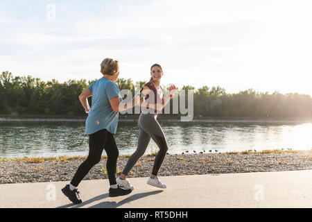 La nipote e nonna divertendosi, jogging insieme al fiume Foto Stock