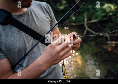 Man mano esca di fissaggio sul gancio di pesca, vista parziale Foto Stock