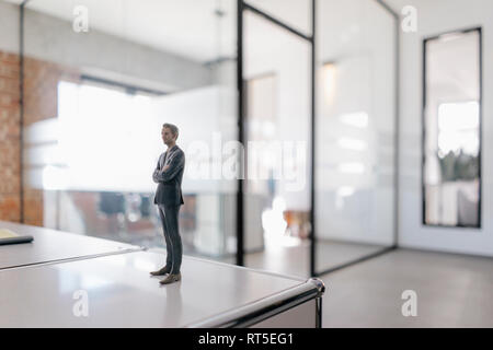 Imprenditore figurina in piedi sulla scrivania in ufficio moderno Foto Stock