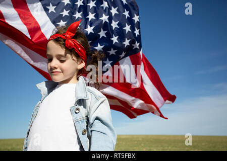 Ragazza con bandiera americana sul campo nel paesaggio remoto Foto Stock