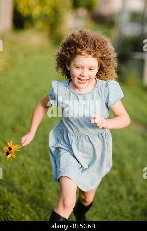 Felice bambina in esecuzione su un prato in giardino Foto Stock