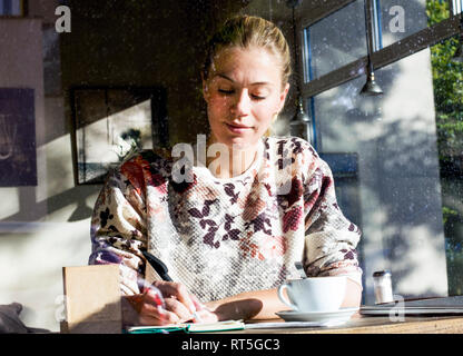 Ritratto di donna in un cafe la scrittura su notebook Foto Stock