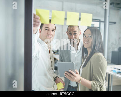 Collega con sticky notes e tablet in ufficio Foto Stock