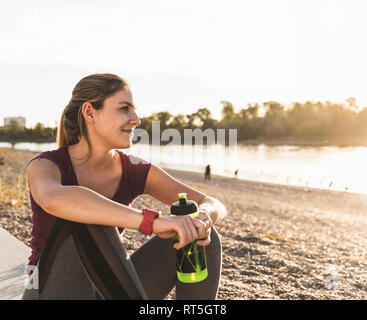 Giovane donna prendendo una pausa dopo aver esercitato sul fiume Foto Stock