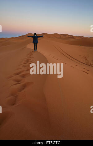 Il Marocco, vista posteriore della donna in piedi sul desert dune al crepuscolo Foto Stock