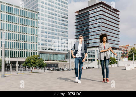 Due colleghi felici a piedi al di fuori di edificio per uffici Foto Stock