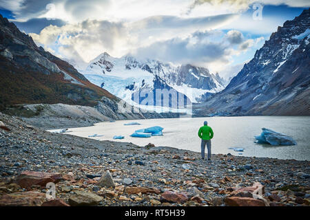 Argentinien, El Chalten, uomo in piedi presso il lago glaciale guardando verso il Cerro Torre Foto Stock