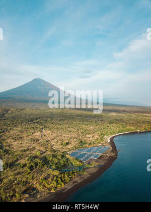 Indonesia, Bali, Amed, vista aerea di allevamento di gamberetti e di vulcano Agung in background Foto Stock