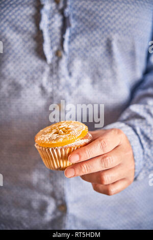 Donna di mano azienda muffin con arancia candita slice, close-up Foto Stock