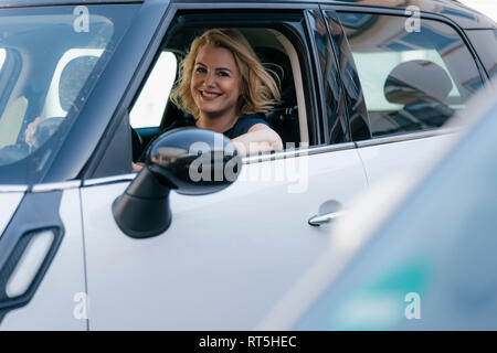 Ritratto di donna sorridente guardando fuori della finestra auto Foto Stock