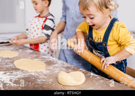 Entusiasta il toddler girl rolling out di pasta di legno con perno di rotolamento Foto Stock