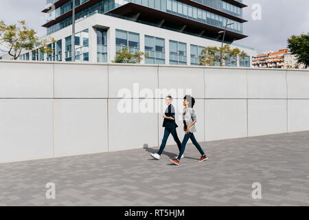 Due colleghi felici a piedi al di fuori di edificio per uffici Foto Stock