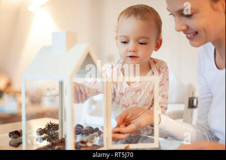 Madre e figlia piccola armeggiare decorativi autunnali casa Foto Stock