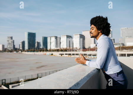 Spagna, Barcellona, uomo appoggiato sulla balaustra godendo la luce solare Foto Stock