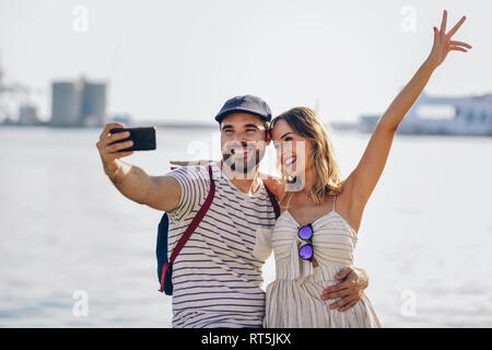 Spagna, Andalusia, Malaga, felice coppia turistica prendendo selfie con lo smartphone al litorale Foto Stock