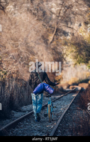 Ragazzo camminando sul treno via con noleggio biciclette Foto Stock