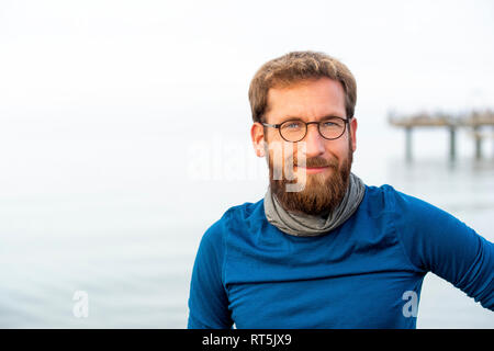 Germania, Rerik, ritratto di uomo barbuto davanti al mare indossando metallo-bordati di occhiali Foto Stock