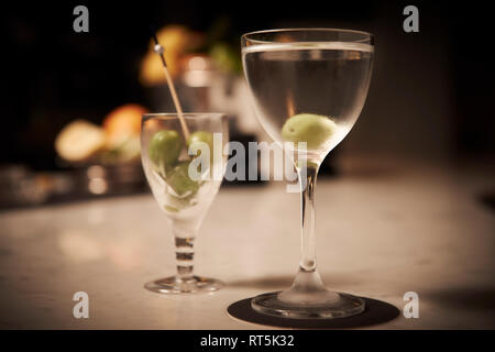 Un refrigerate Martini con un vetro di ricambio di olive verdi in un suggestivo wine bar. Foto Stock