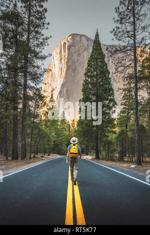 Stati Uniti d'America, in California, del Parco Nazionale Yosemite, uomo a camminare sulla strada con El Capitan in background Foto Stock