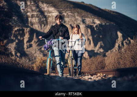 Un ragazzo e una ragazza camminare sul treno via con le biciclette Foto Stock