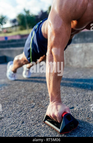 Close-up di barechested uomo muscolare facendo push-up all'aperto Foto Stock