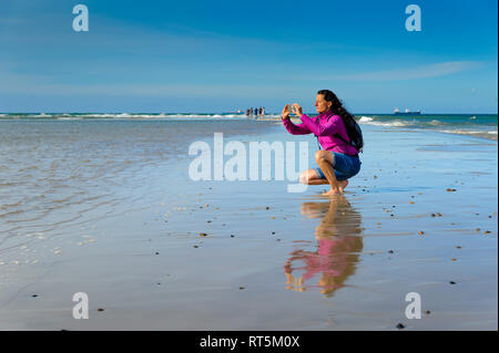 Danimarca, nello Jutland, Skagen, Grenen, donna di scattare le foto del Mare del Nord e del Mar Baltico Foto Stock