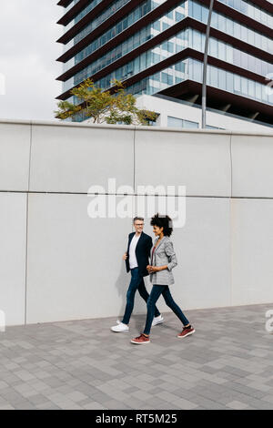 Due colleghi felici a piedi al di fuori di edificio per uffici Foto Stock