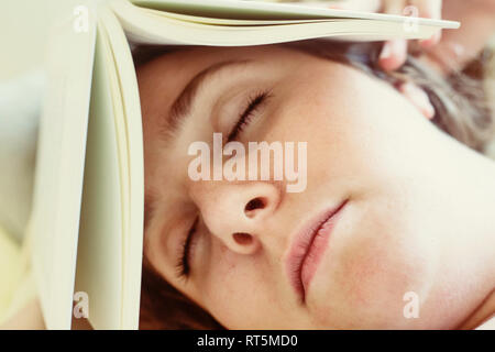 Ritratto di giovane donna che dorme con libro sulla testa, close-up Foto Stock