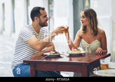 Coppia sorridente tintinnanti di birra in un ristorante sulla strada Foto Stock