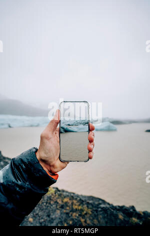 3D montage dell uomo prendendo immagini dello smartphone dell Islanda il paesaggio Foto Stock