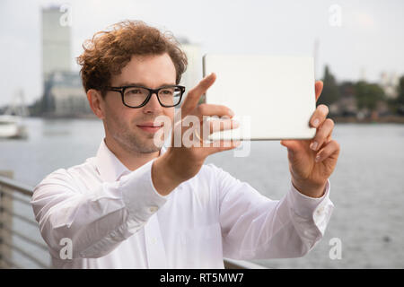 Germania Berlino, ritratto di imprenditore di prendere foto con tavoletta digitale Foto Stock