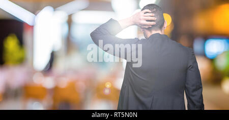 Giovane sacerdote cristiano su sfondo isolato indietro pensando di dubbio con la mano sulla testa Foto Stock