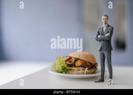 Imprenditore in miniatura statuetta in piedi accanto al fast food Foto Stock