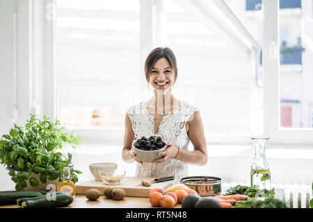 La donna la preparazione di un alimento sano nella sua cucina, tenendo una ciotola di ciliegie Foto Stock