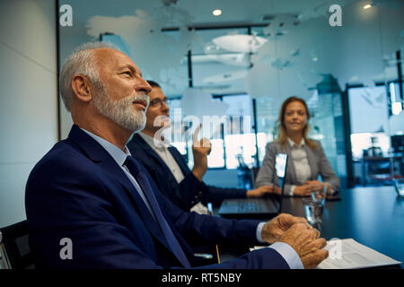Ritratto di imprenditore senior di ascolto in una riunione Foto Stock