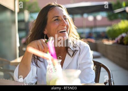 Donna felice seduto in un bar con un bicchiere da cocktail Foto Stock