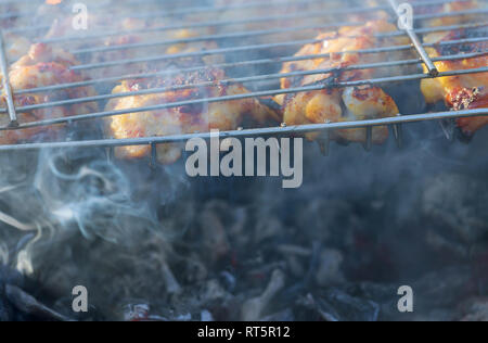 Gustoso pollo grigliato gamba sopra le fiamme su un barbecue. Foto Stock