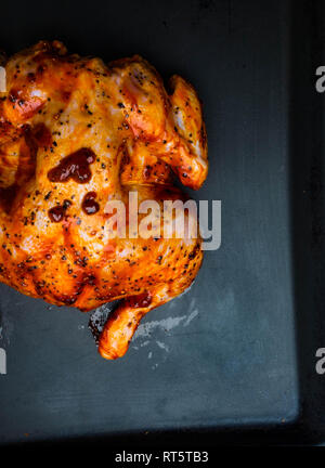 Tutto il pollo crudo vassoio da forno, marinato e pronto a cucinare con spezie, salsa di soia per cucinare. su sfondo nero. Foto Stock