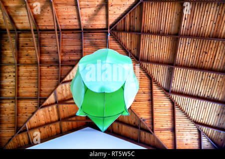 Un paralume verde/lampadario/apparecchio di illuminazione sospeso da un altissimo soffitto in legno. Foto Stock