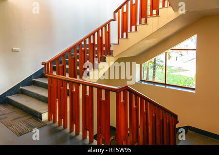 Una rampa di scale con ringhiera in legno a uno dell'edificio a Golkonda Resorts and Spa, Hyderabad, Telangana, India. Foto Stock