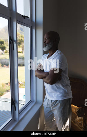 Senior uomo guardando attraverso la finestrella a casa Foto Stock