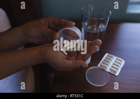 Donna senior di assumere un farmaco con un bicchiere di acqua nel letto di casa Foto Stock