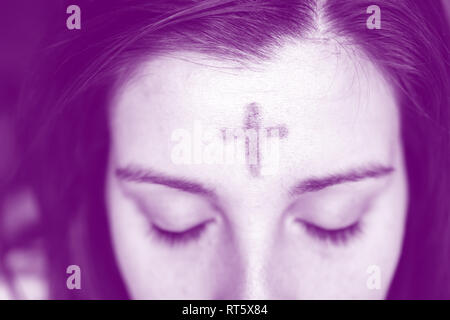 Vicino la donna con la croce sulla fronte in osservanza del Mercoledì delle Ceneri con sovrapposizione di colore viola Foto Stock