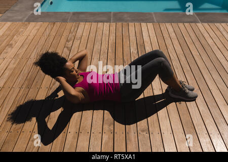 Donna eseguendo crunch esercizio nel cortile di casa Foto Stock