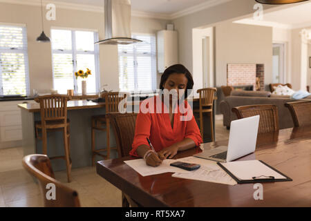 Donna calcolo fatture a casa Foto Stock