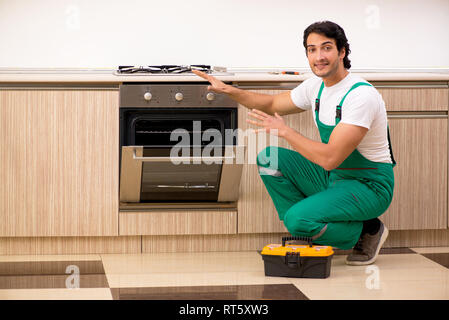 Giovane imprenditore riparazione di forno in cucina Foto Stock